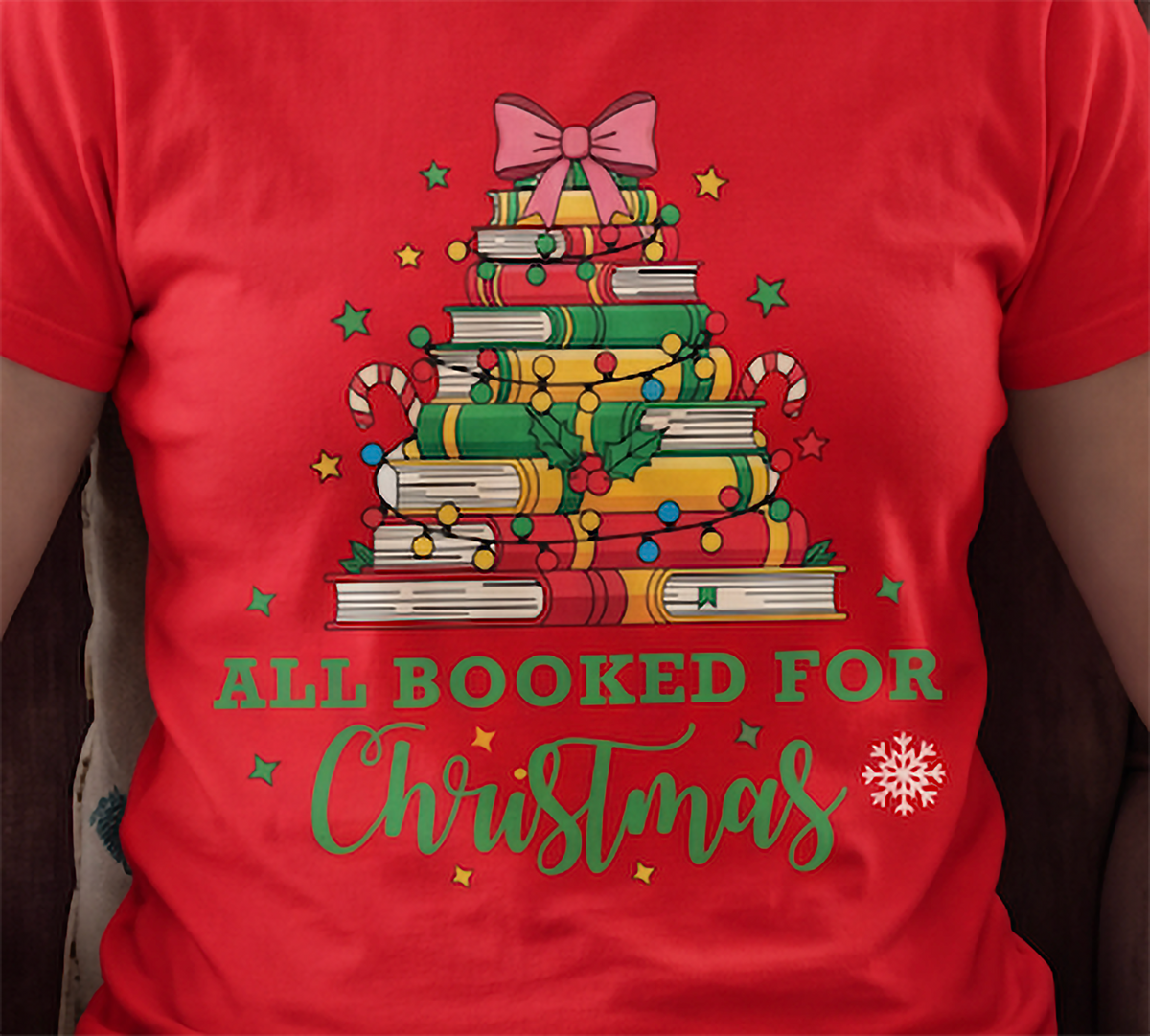 Close-up of red All Booked for Christmas shirt featuring the festive stacked books and holiday decorations.