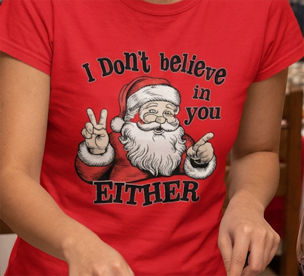 Close-up of red funny Santa Christmas shirt featuring white I Don't Believe in You Either text and vintage Santa artwork.