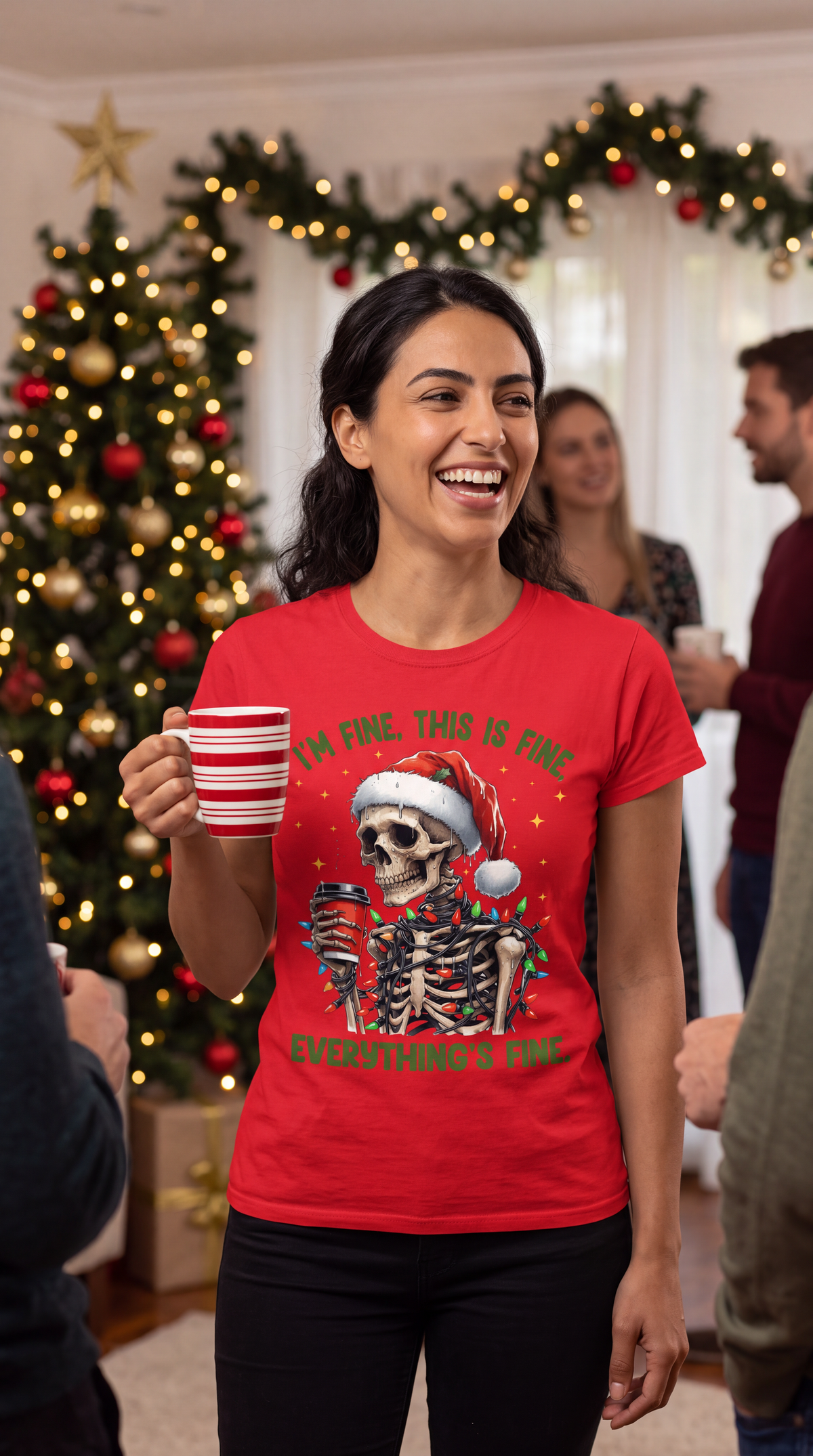 Woman wearing red I’m Fine Everything’s Fine skeleton Christmas shirt near a decorated Christmas tree.