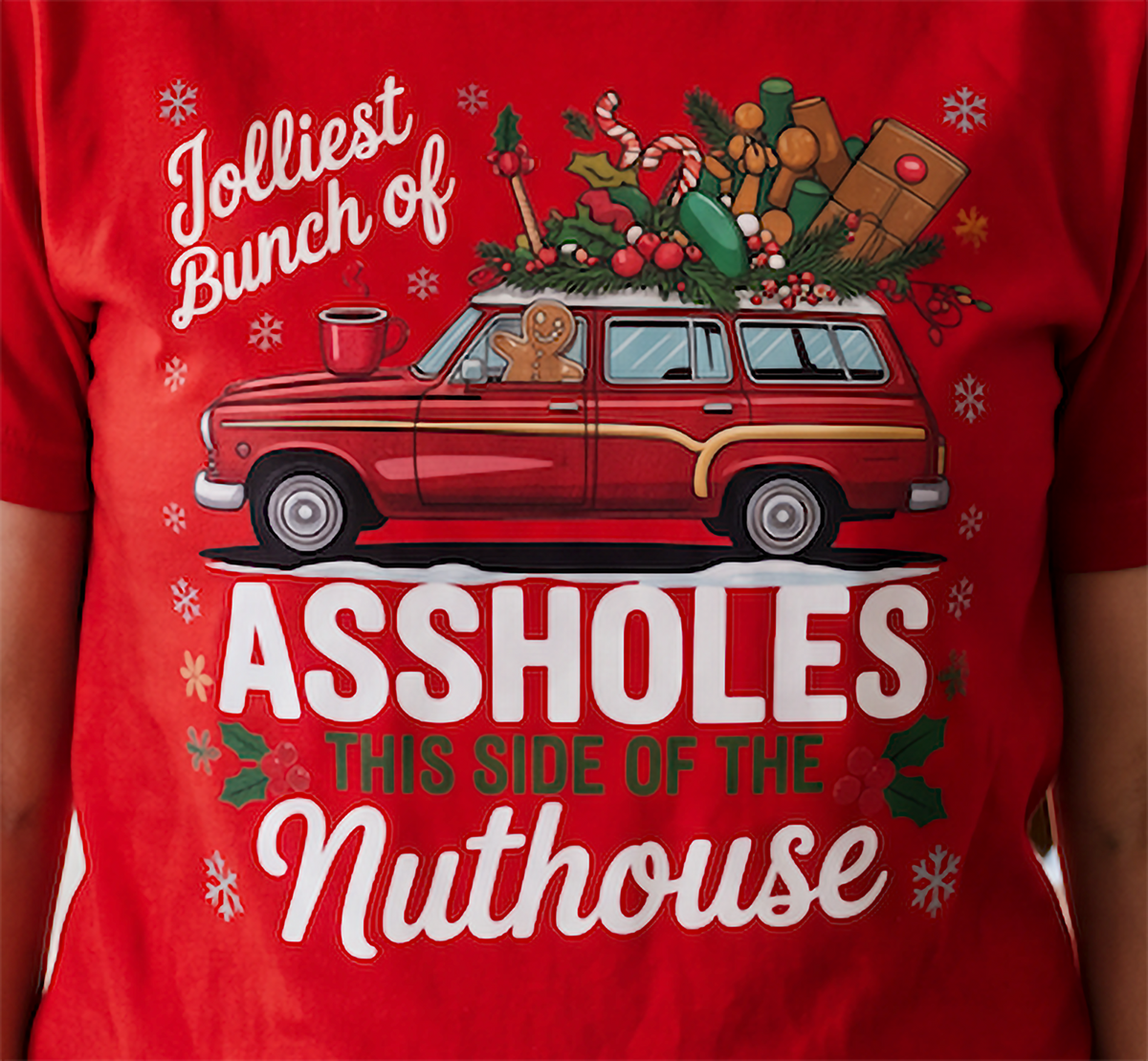 Close-up of Jolliest Bunch of Assholes Christmas graphic printed on red shirt.