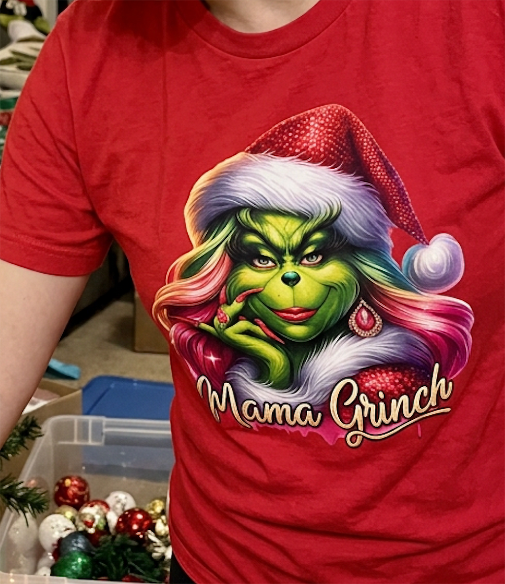 Close-up of red Mama Grinch Christmas tee showing vibrant pink hair, Santa hat and sassy green character.