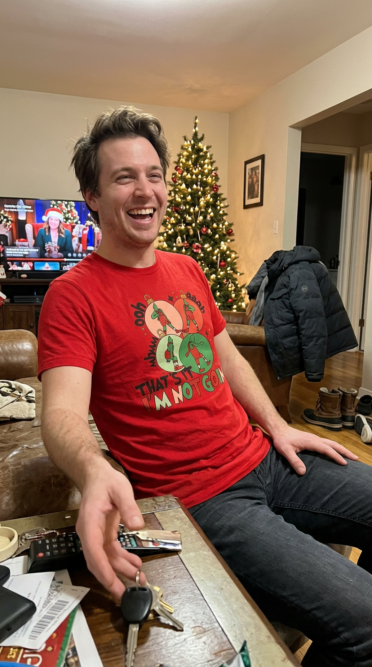 Red Lifestyle: Woman wearing a red Grinch-inspired Christmas graphic tee while sitting at a casual holiday gathering.