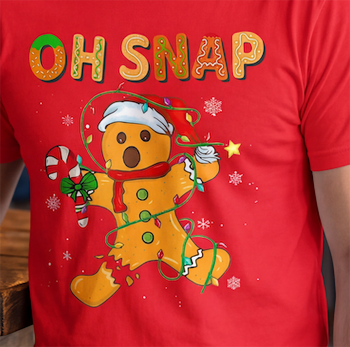 Close-up of colorful Oh Snap gingerbread Christmas design on red shirt.
