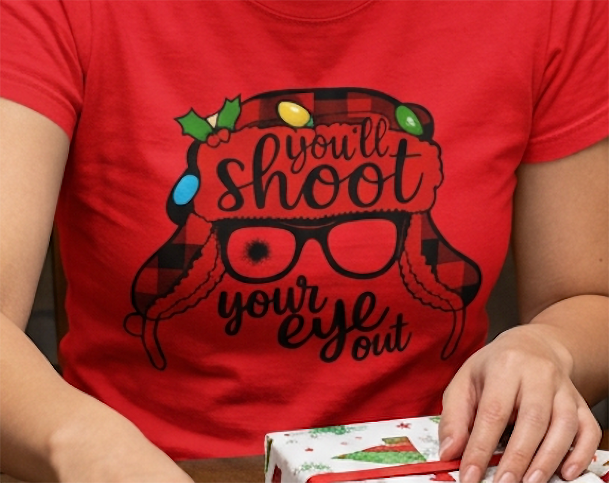 Close-up of red Christmas graphic tee showing You'll Shoot Your Eye Out design and retro holiday movie humor