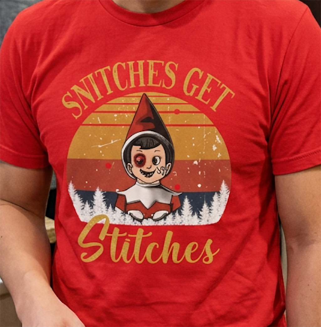 Close-up of vintage Christmas elf graphic with Snitches Get Stitches lettering on a red holiday t-shirt.