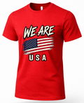 A red short-sleeve crewneck t-shirt featuring a distressed graphic print of the American flag with the text 'WE ARE' above and 'USA' below, displayed on a clean white background.