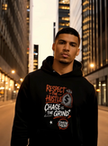 Man wearing black “Respect the Hustle Chase the Grind” graphic hoodie in a city street setting