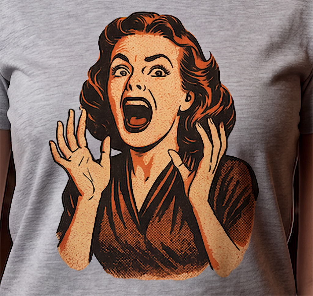 A close-up of a heather gray t-shirt featuring a retro-style graphic print of a shocked woman with wavy hair, raised hands, and an open mouth in orange, brown, and beige tones.