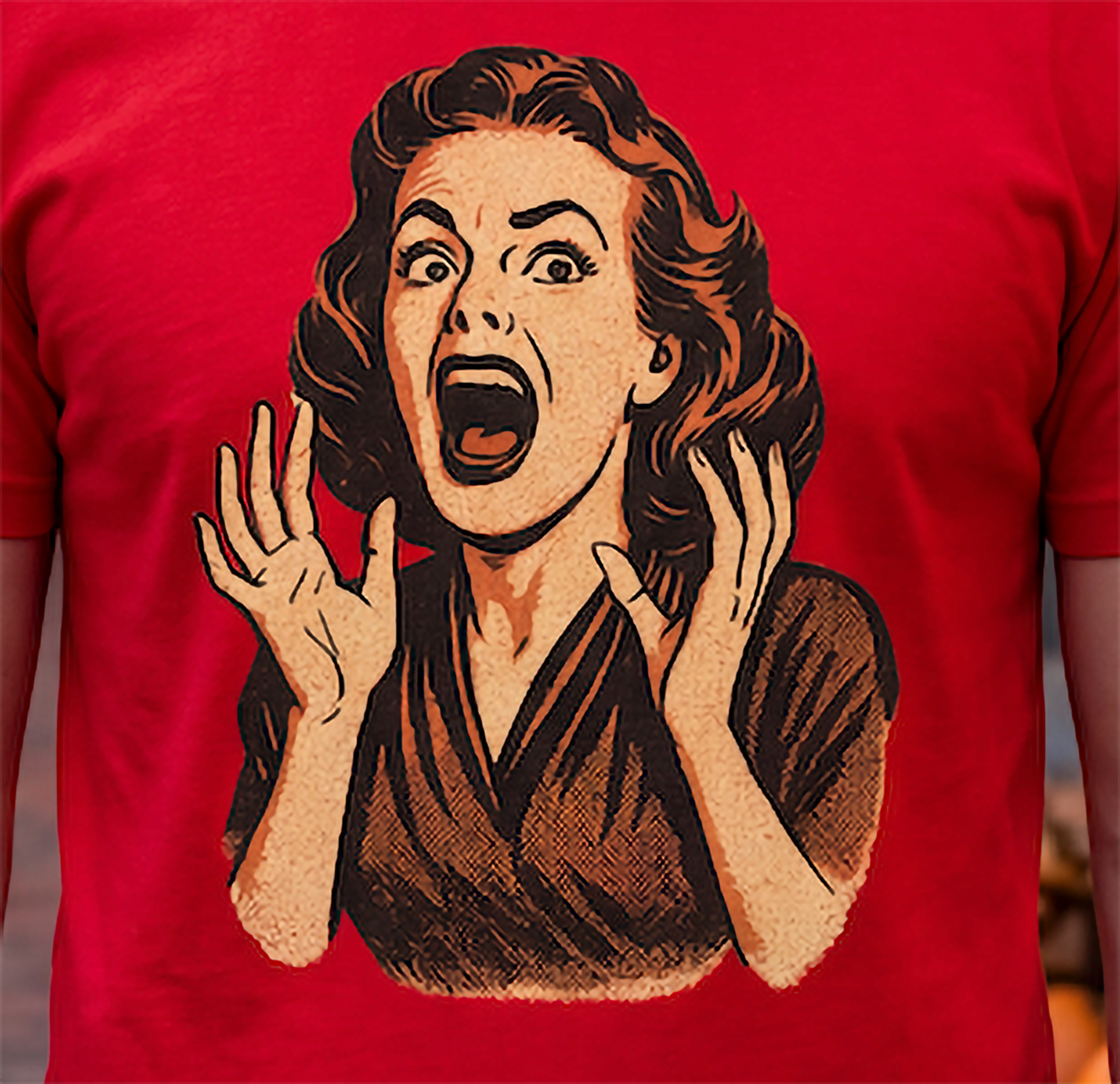 A close-up of a red short-sleeve T-shirt worn by a person, featuring a large retro-style graphic print of a shocked woman with raised hands on the front.