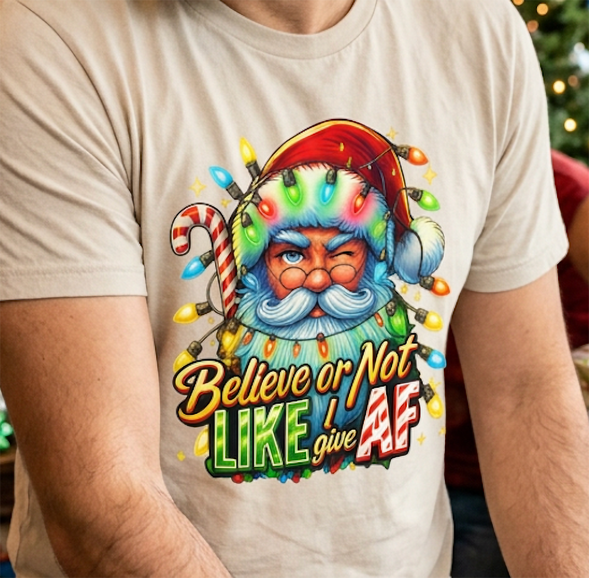 Sand Close-Up: Detailed close-up of the Believe or Not Like I Give AF Christmas design on sand-colored fabric featuring Santa and festive lights.