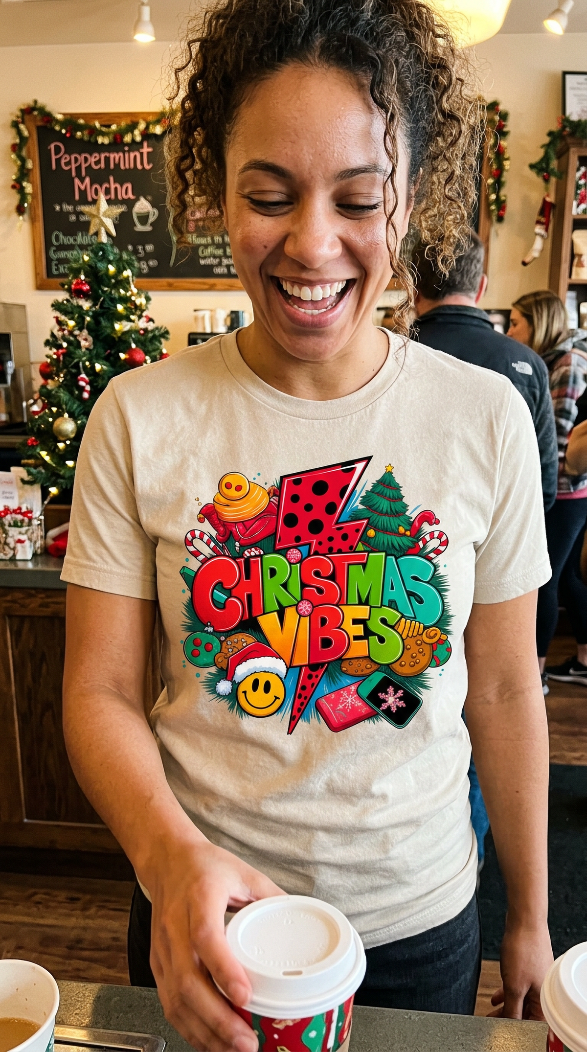 Lifestyle –Sand: Woman wearing a heather sand Christmas Vibes graphic t-shirt at a festive holiday gathering.