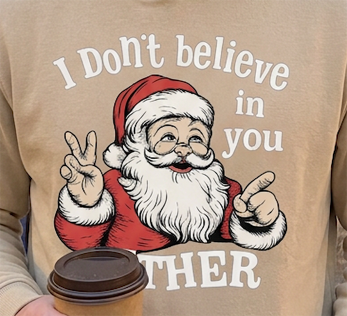 Close-up of I Don’t Believe in You Either Santa graphic on sand Christmas hoodie