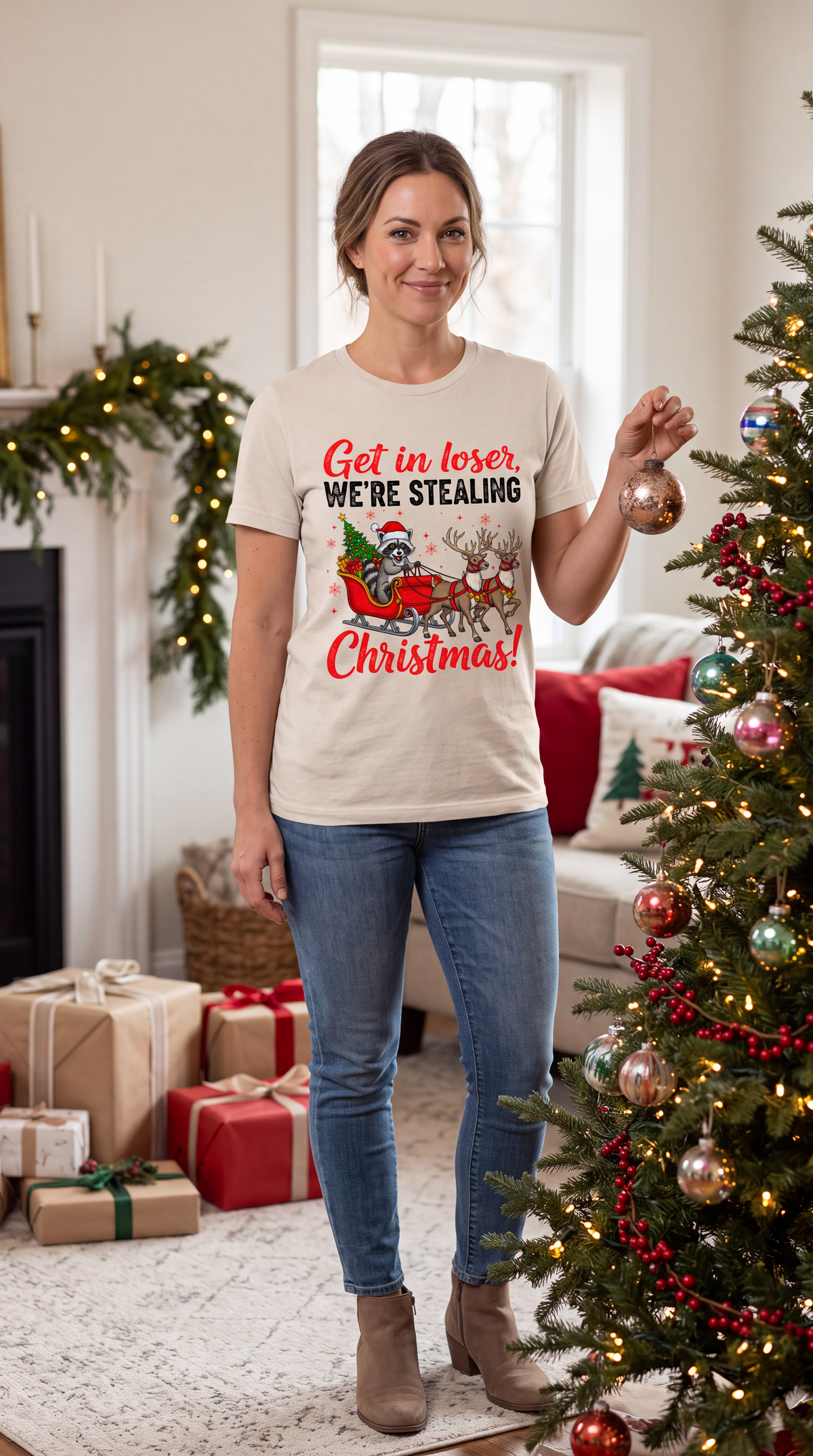 Woman wearing a sand Get in Loser We’re Stealing Christmas graphic tee in a festive Christmas setting.