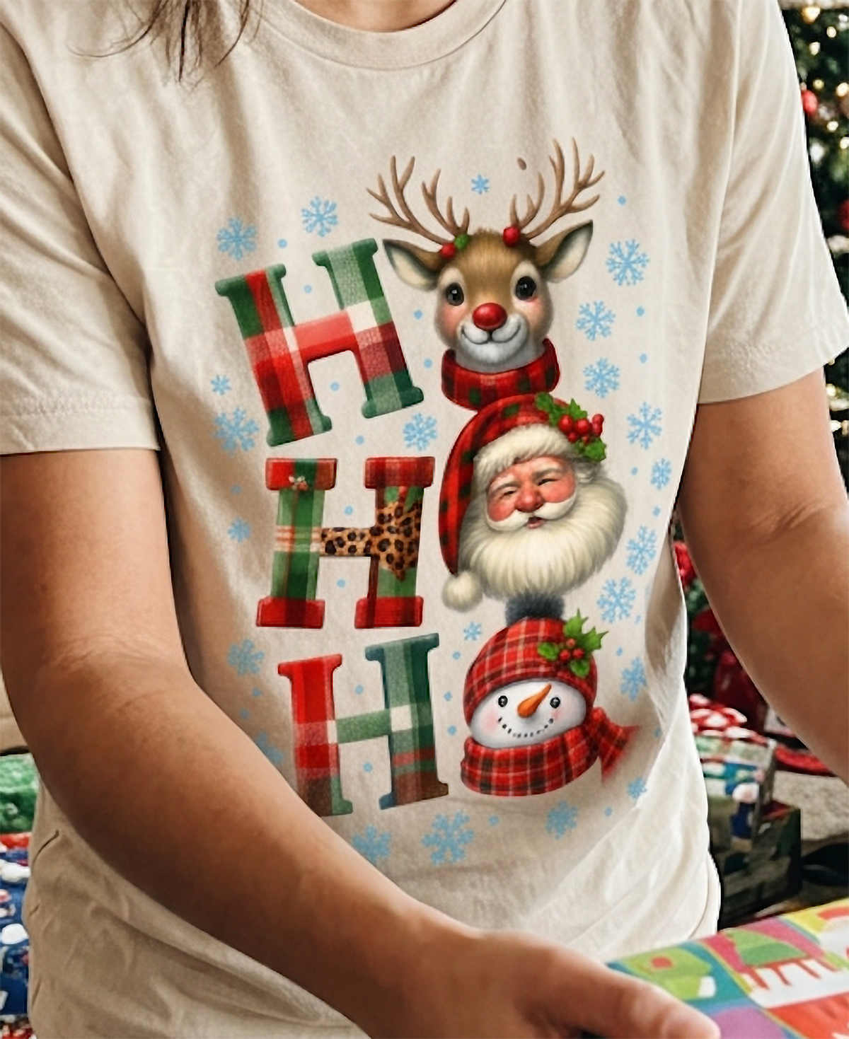 Close-up of sand Christmas shirt featuring cute Santa Claus, reindeer, snowman and blue snowflake decorations.