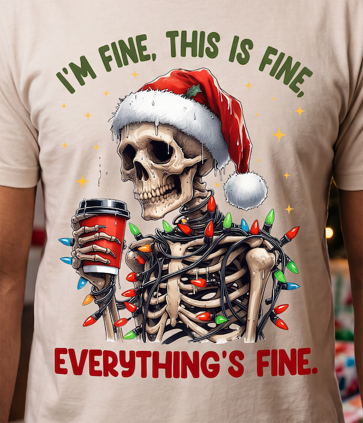 Close-up of I’m Fine Everything’s Fine Christmas skeleton graphic printed on a sand T-shirt.