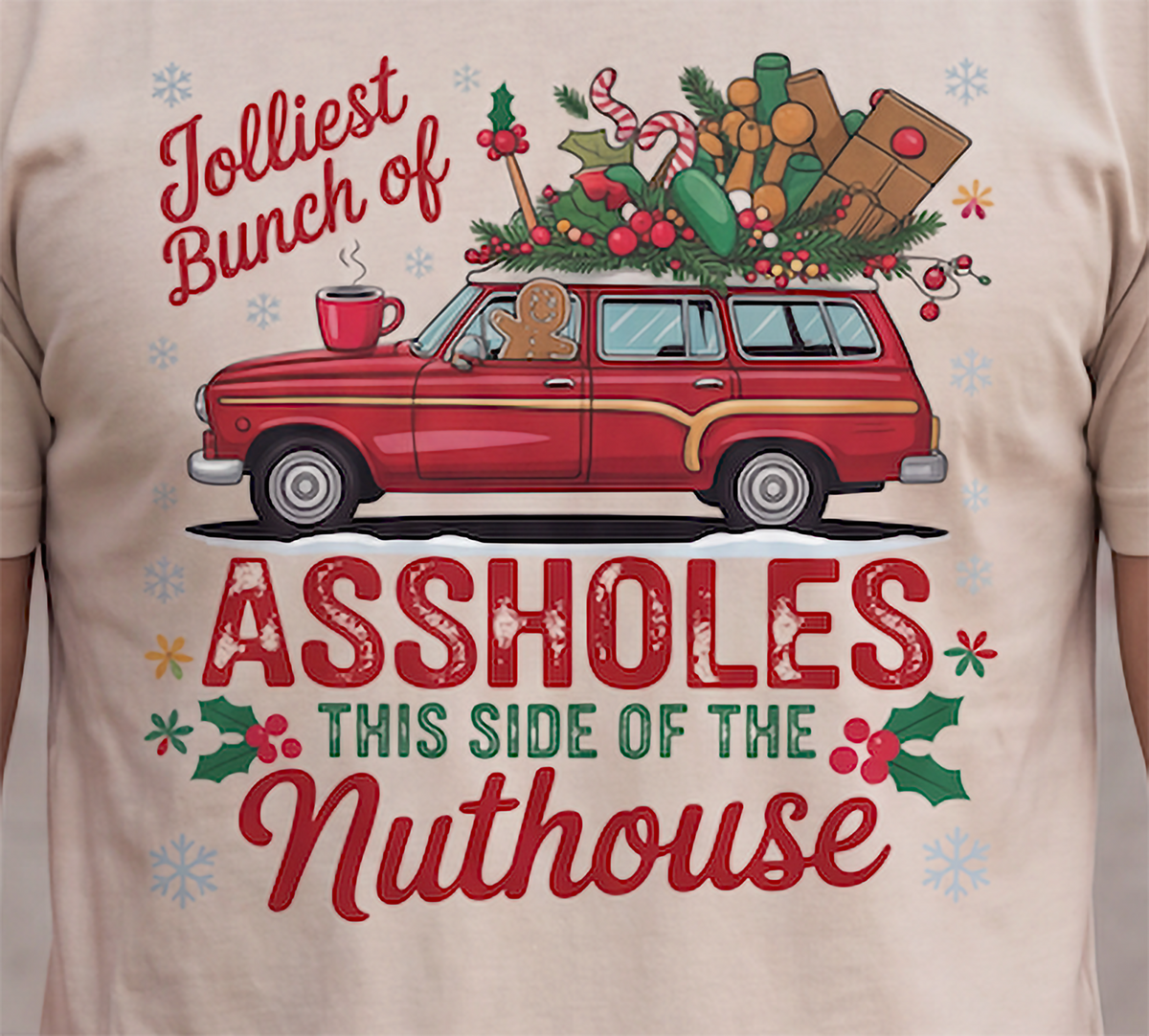 Close-up of Jolliest Bunch of Assholes Christmas graphic printed on sand shirt.