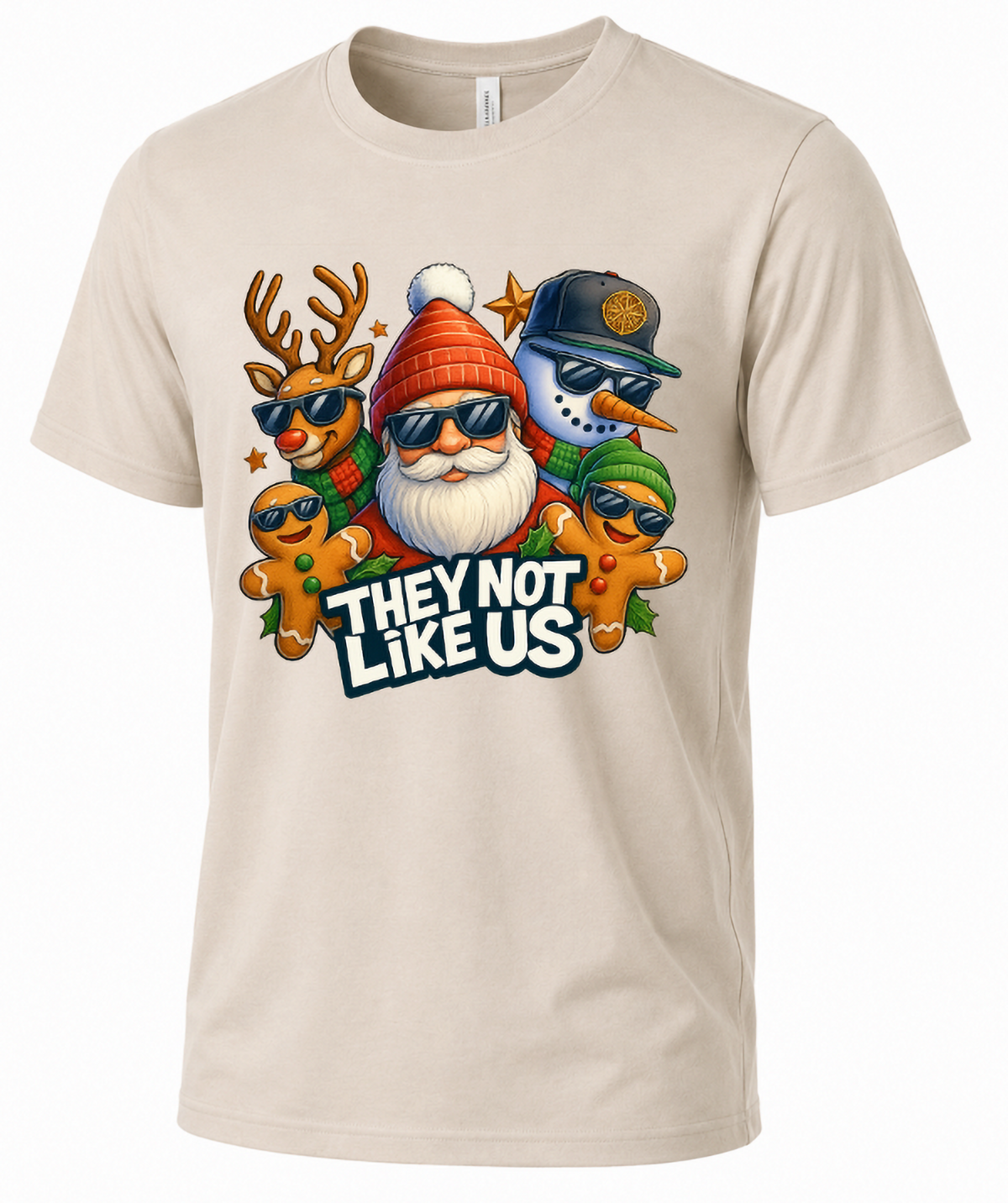Sand-colored Christmas graphic t-shirt featuring They Not Like Us holiday crew design with Santa, reindeer, snowman, and gingerbread characters.