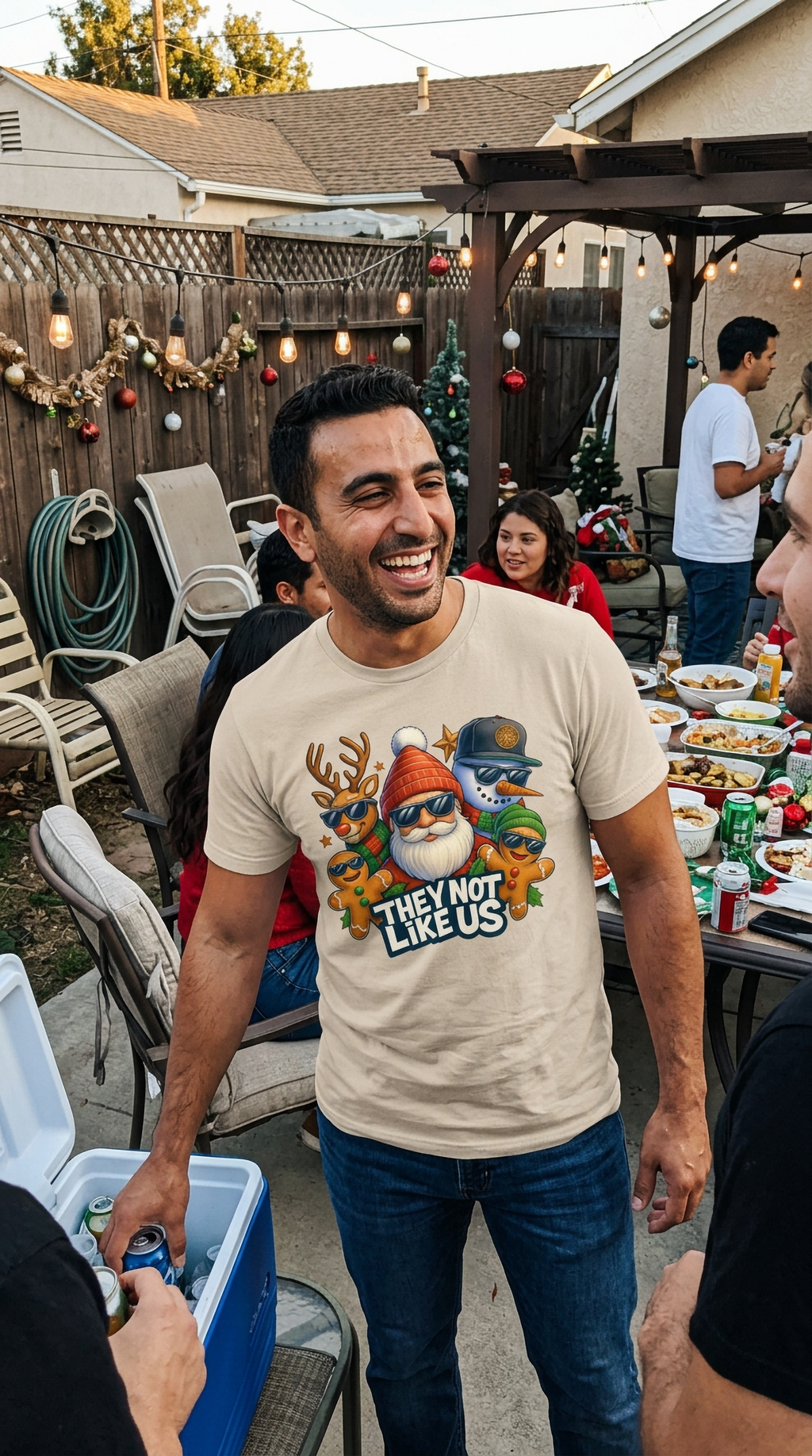Sand Lifestyle: Man wearing a sand-colored They Not Like Us Christmas t-shirt with a festive Santa and holiday character graphic.