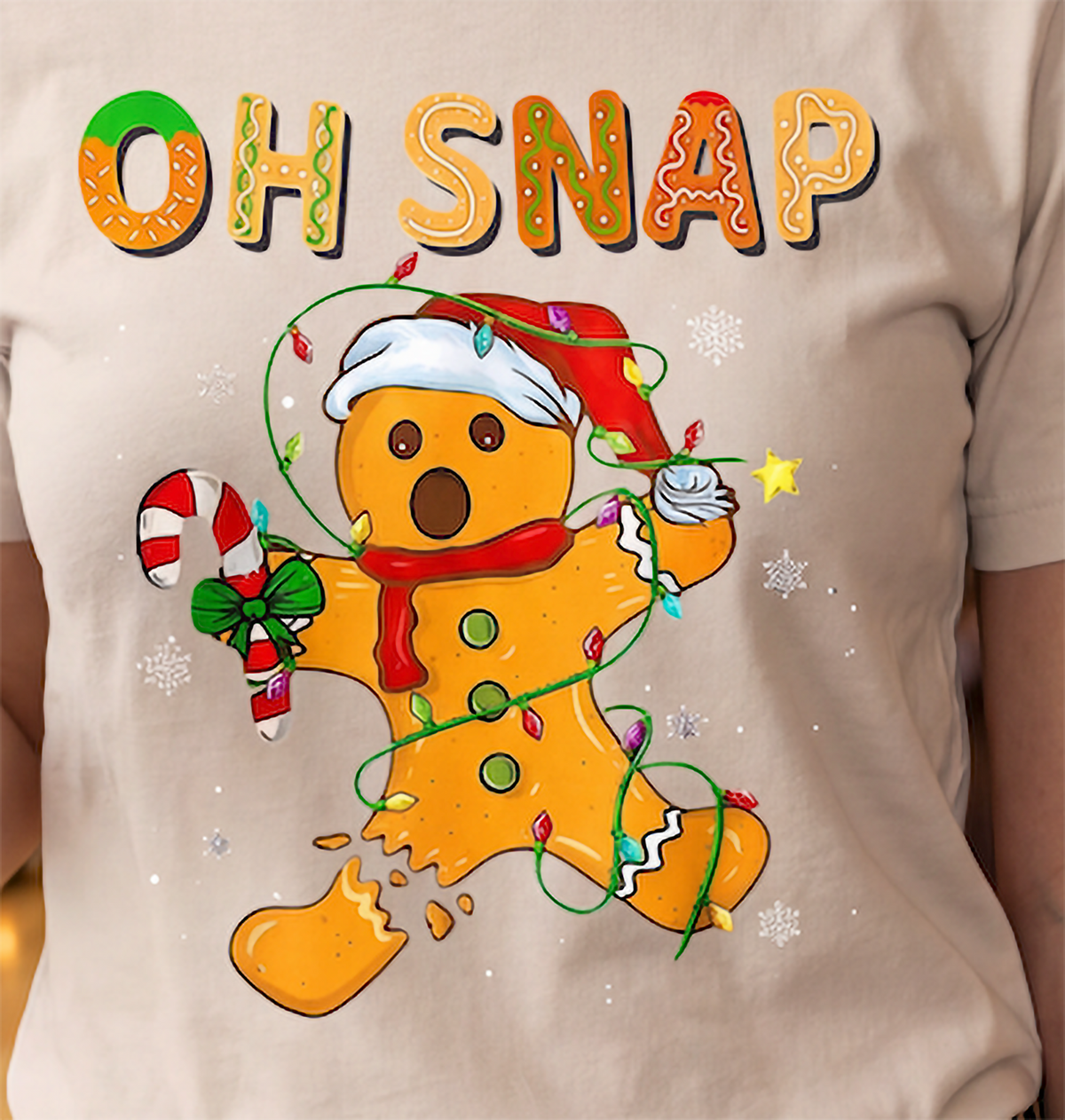 Close-up of Oh Snap gingerbread man Christmas graphic on sand shirt.