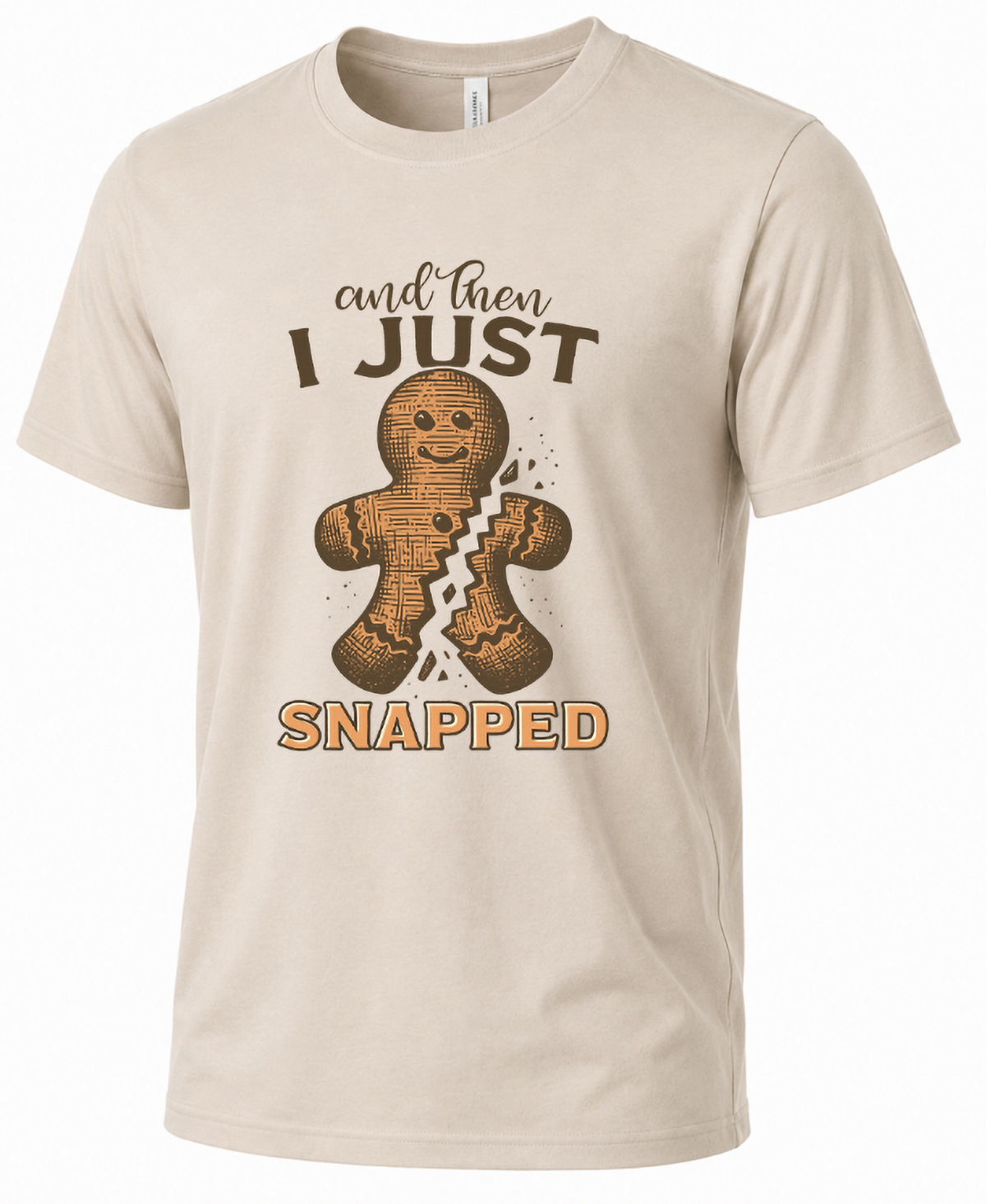 Sand Mockup: Sand-colored unisex Christmas graphic t-shirt featuring a broken gingerbread man and the funny saying And Then I Just Snapped.