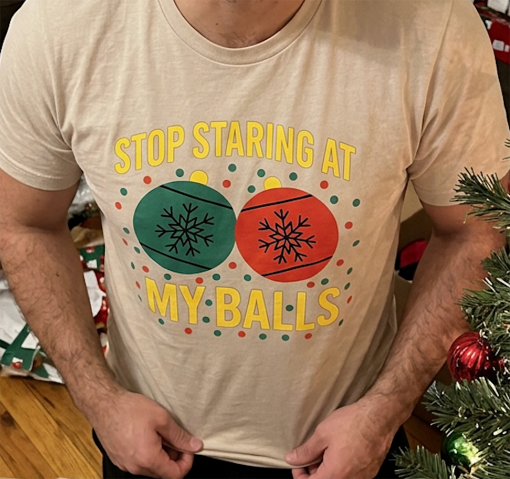Close-up of sand Christmas t-shirt featuring colorful ornaments and sarcastic adult holiday saying.
