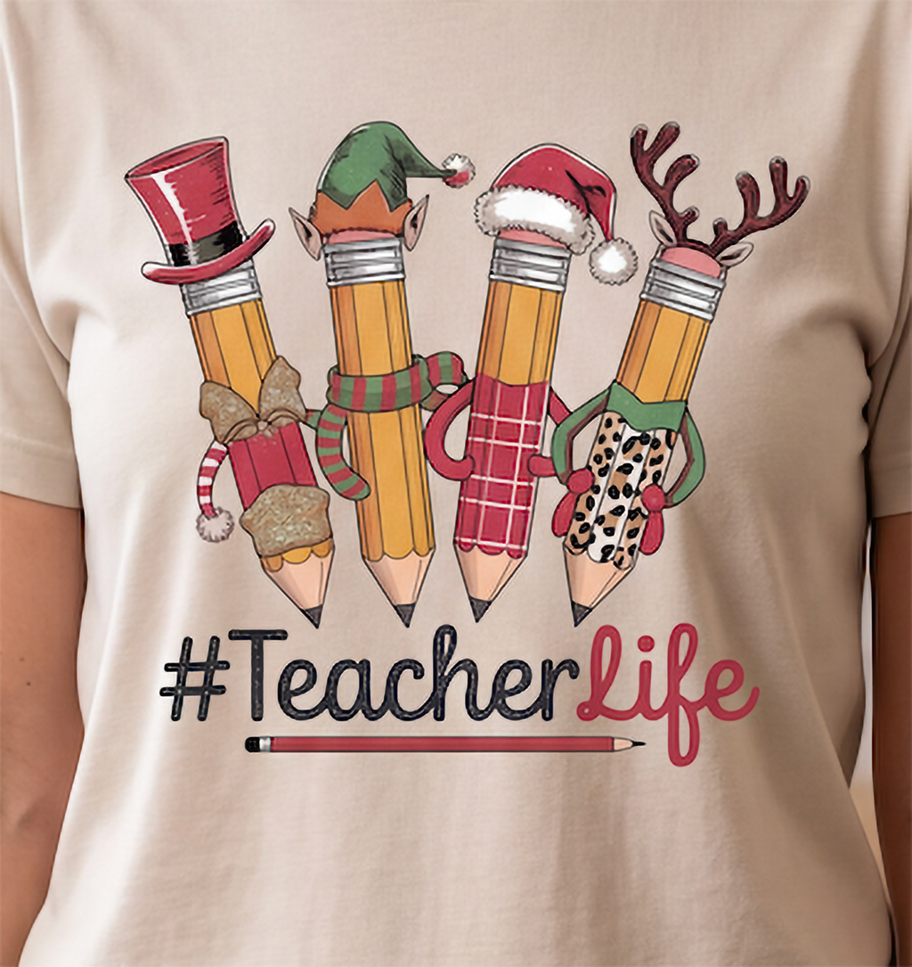 Close-up of sand Teacher Life Christmas shirt with Santa, elf, snowman and reindeer pencil design.