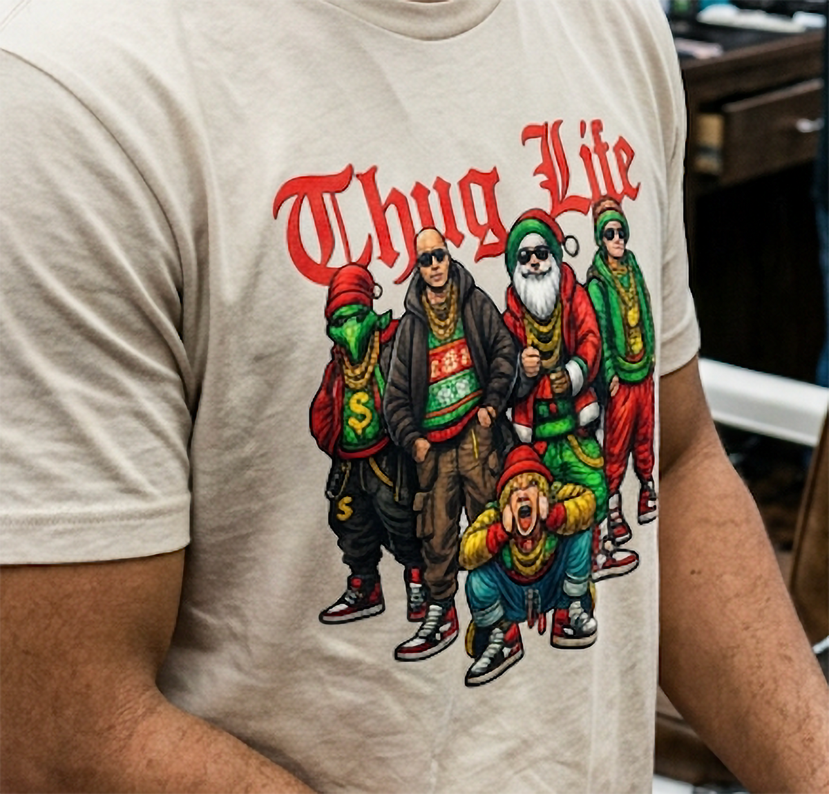 Close-up of sand Christmas graphic t-shirt showing Thug Life lettering and hip hop-inspired holiday characters