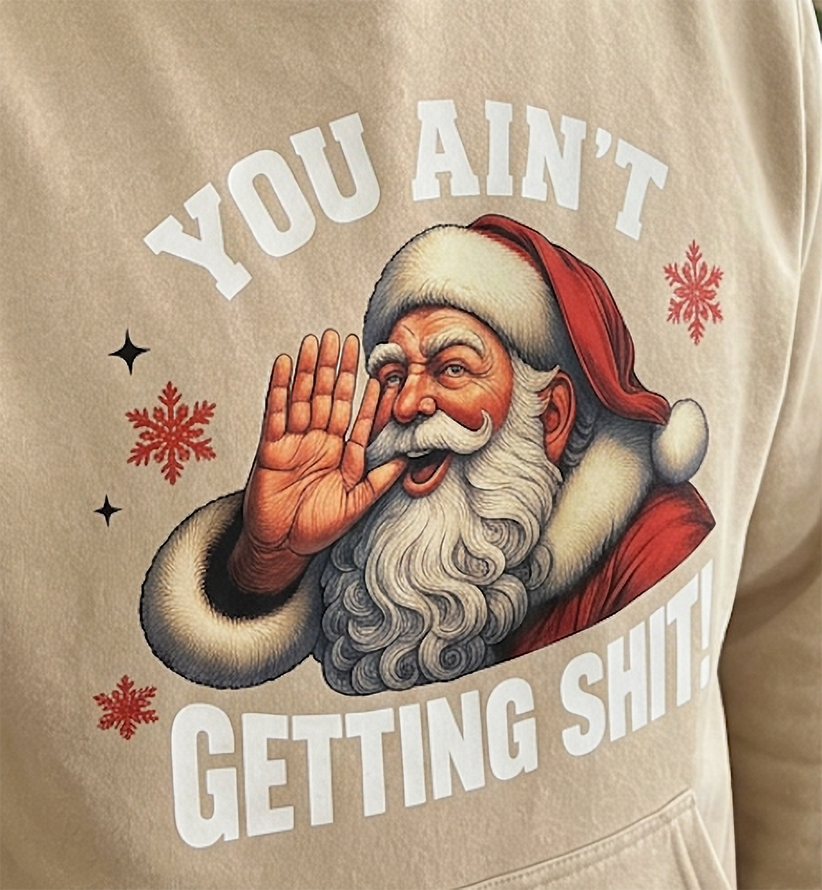 Close-up of You Ain’t Getting Shit Santa graphic on sand Christmas hoodie
