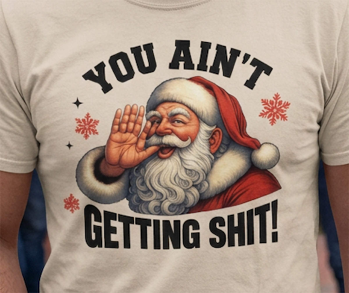 Sand Close-Up: Detailed close-up of sarcastic Santa Christmas artwork on a sand-colored graphic t-shirt featuring festive snowflakes.