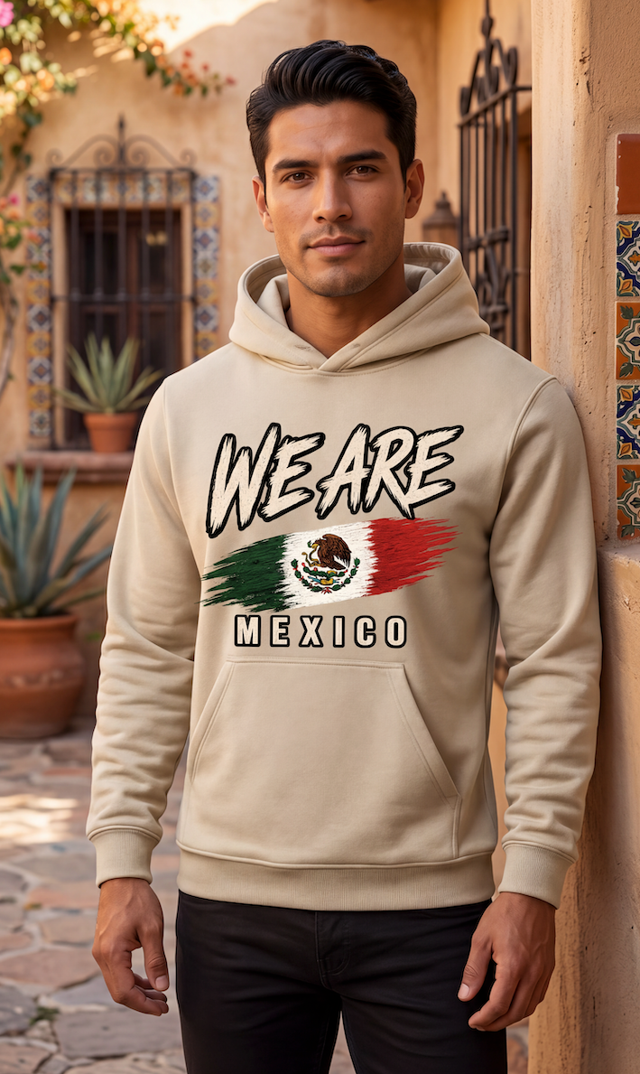 A man wearing a beige hoodie with a 'WE ARE MEXICO' graphic featuring the Mexican flag, standing in front of a warm-toned tiled wall.