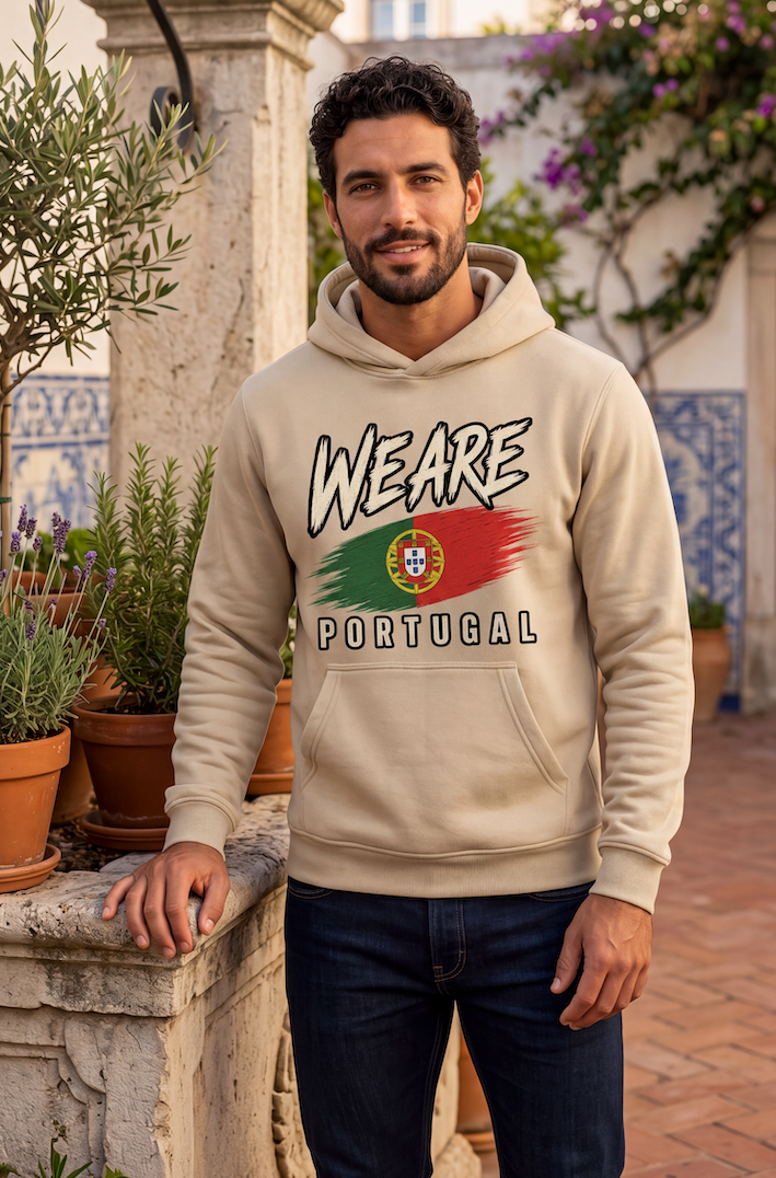 A man wearing a beige hoodie with a 'WE ARE PORTUGAL' graphic featuring the Portuguese flag, standing outdoors on a stone terrace with potted plants and tiled walls.