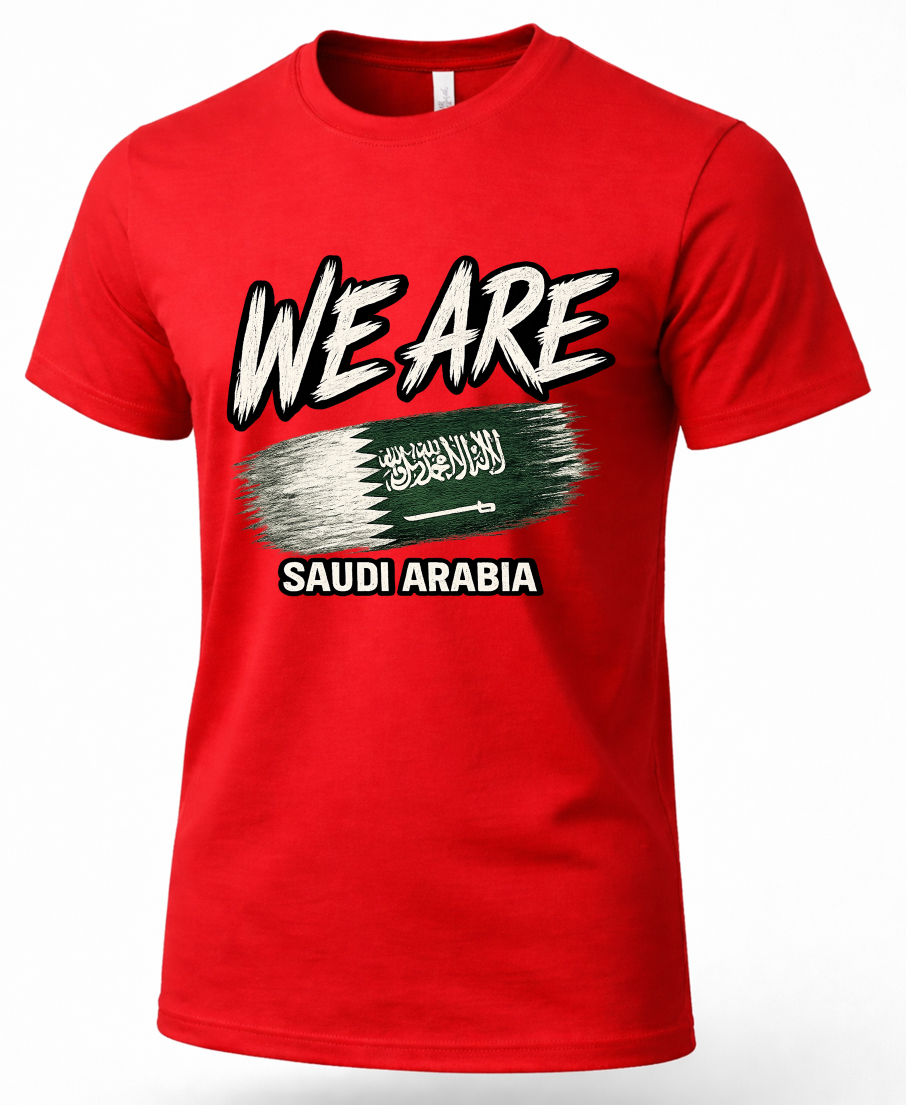 A red short-sleeve crewneck t-shirt featuring a graphic print with the text 'WE ARE' in white with black outlines, a distressed green flag design with white script, and 'SAUDI ARABIA' in white text below.
