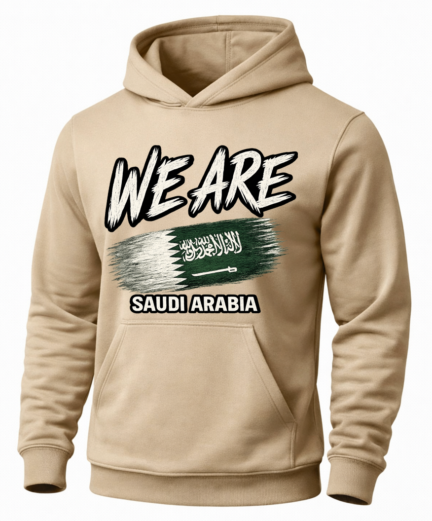 A beige pullover hoodie with a graphic print on the front. The design features the text 'WE ARE' in a stylized white font with black outlines, a horizontal Saudi Arabian flag graphic in the center, and 'SAUDI ARABIA' printed below in white text inside a black rectangle.