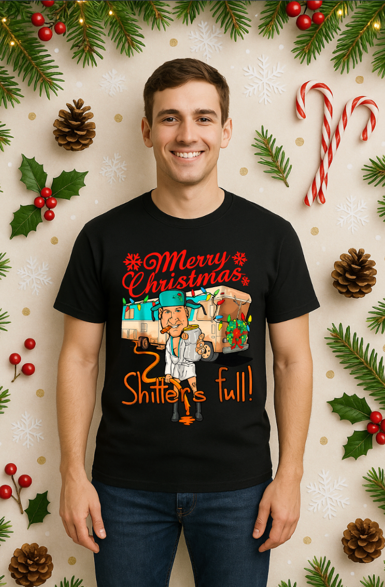 Smiling man wearing a black “Merry Christmas, Shitter’s Full” graphic t-shirt, standing in front of a festive holiday background with candy canes, pine branches, and Christmas decorations.