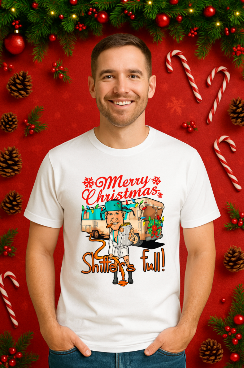 Smiling man wearing a white “Merry Christmas, Shitter’s Full” graphic t-shirt, standing in front of a festive red holiday background with candy canes, pine cones, and Christmas greenery.