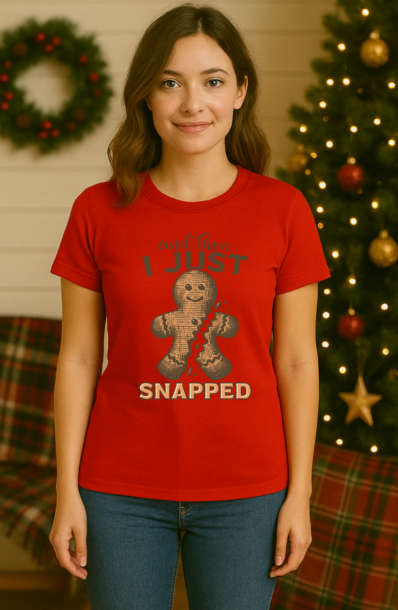 Woman wearing a red “And Then I Just Snapped” gingerbread Christmas shirt, standing in front of a decorated Christmas tree and holiday wreath.