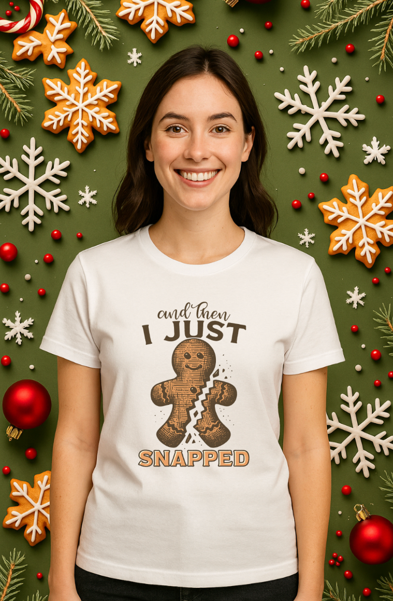 Woman wearing a white “And Then I Just Snapped” gingerbread Christmas shirt, standing in front of a festive green background with ornaments, snowflakes, and holiday decorations.