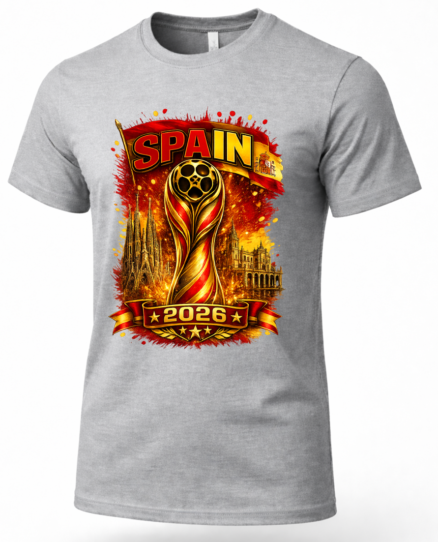 A heather gray short-sleeve crewneck t-shirt featuring a large graphic print for the 2026 FIFA World Cup in Spain. The graphic displays the FIFA World Cup trophy in gold and red, the word 'SPAIN' in bold letters, the year '2026', and silhouettes of the Santiago and Madrid stadiums, all set against a fiery red and orange background.