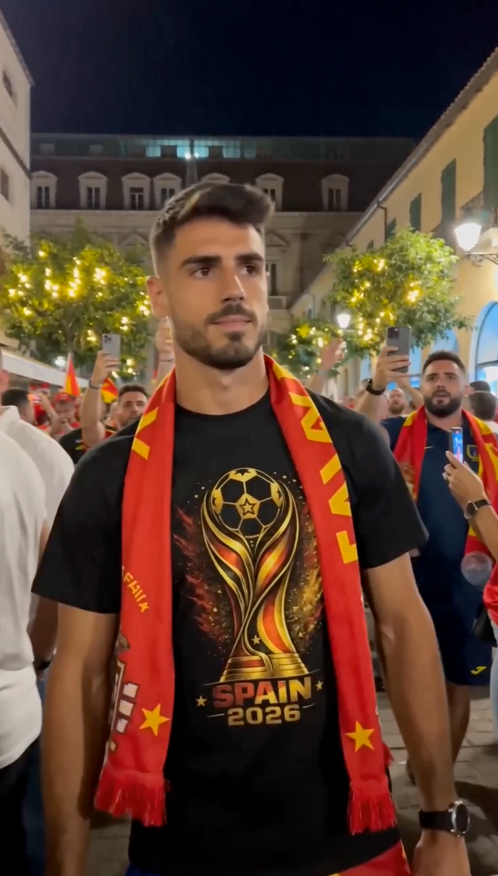 Spain football fan wearing black Spain 2026 soccer graphic T-shirt during nighttime street celebration