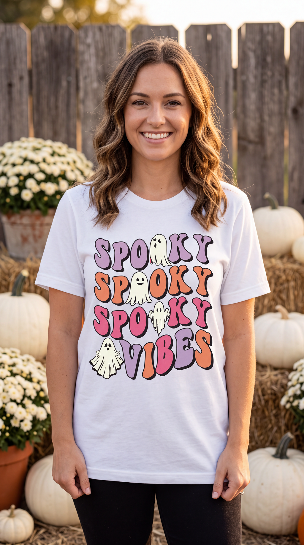 Woman wearing white Spooky Vibes Halloween shirt with colorful retro ghost graphic in a fall pumpkin setting