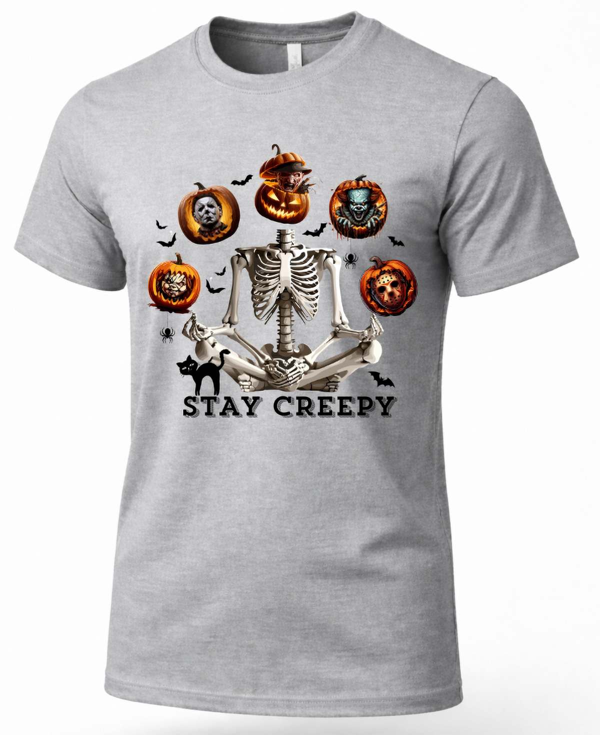 A heather gray short-sleeve crewneck t-shirt featuring a Halloween graphic of a skeleton sitting cross-legged with jack-o'-lanterns, bats, a black cat, and the text 'STAY CREEPY'.