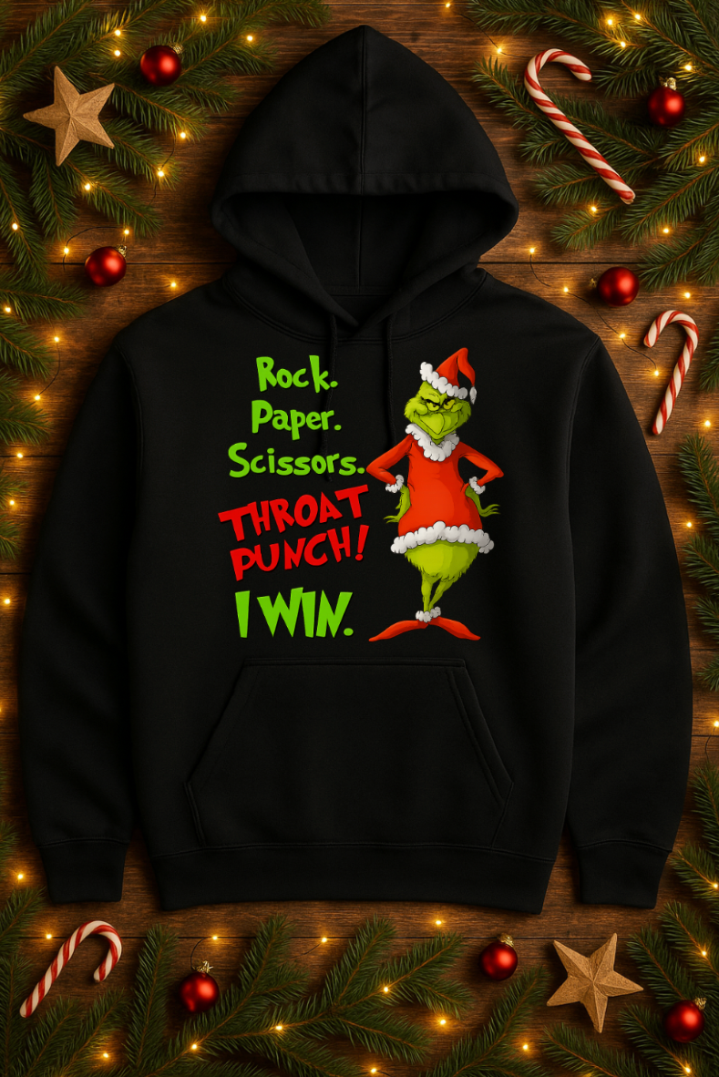 Black Christmas hoodie with a funny Rock Paper Scissors Throat Punch design, displayed on a festive holiday background with lights, pine branches, and candy canes.