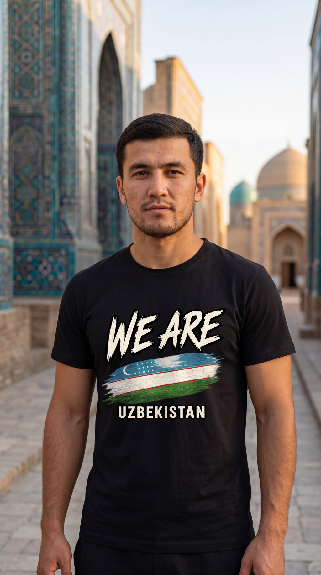 A man wearing a black graphic t-shirt with the text 'WE ARE UZBEKISTAN' and a stylized flag design, standing in front of a historic tiled building.