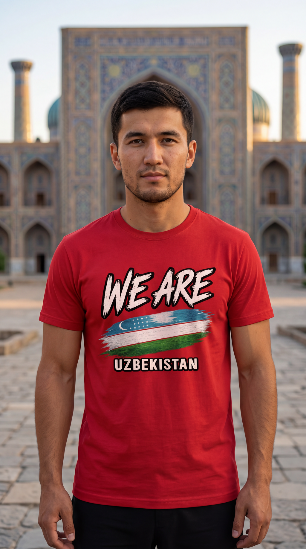 A man wearing a red graphic t-shirt with 'WE ARE UZBEKISTAN' and the Uzbek flag printed on the front, standing in front of a historic tiled architectural landmark.