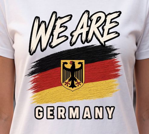 A close-up of a white short-sleeve T-shirt worn by a person, featuring a graphic print with the words 'WE ARE' and 'GERMANY' in bold outlined lettering, a black, red, and yellow flag design, and the German eagle emblem.