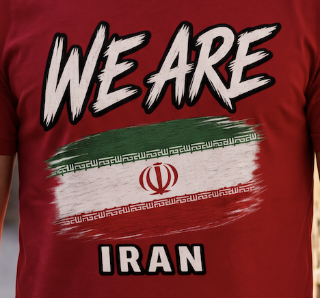 A close-up of a red t-shirt featuring a graphic print with the text 'WE ARE' and 'IRAN' in white with black outlines, overlaid on a stylized green, white, and red flag design with Arabic calligraphy.