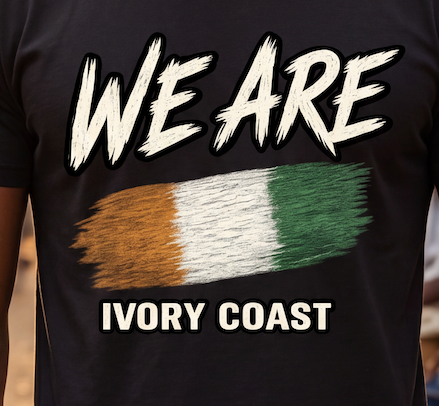 Close-up of a black T-shirt worn by a person, featuring the text 'WE ARE' above a brushstroke-style tricolor flag in orange, white, and green, with 'IVORY COAST' below.