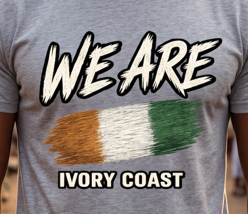 A close-up of a heather gray t-shirt featuring a graphic design with the text 'WE ARE' and 'IVORY COAST' in white with black outlines, and a textured tricolor flag in orange, white, and green resembling the Irish flag.