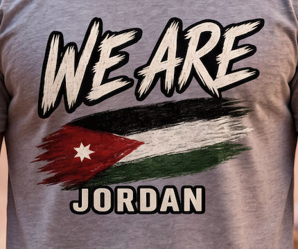 A close-up of a heather gray t-shirt featuring a graphic print that reads 'WE ARE JORDAN' with a distressed, painted Jordan flag design in the center.