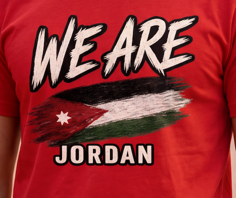A close-up of a red short-sleeve t-shirt worn by a person, featuring a graphic print with the text 'WE ARE' above a stylized Palestinian flag and 'JORDAN' below.